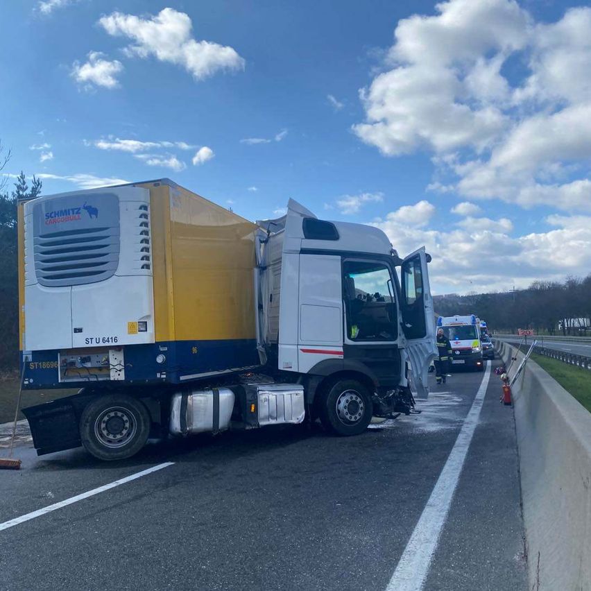 Ein LKW mit Schmitz Cargobull-Marke steht am Straßenrand, die Tür ist offen. Ein Rettungswagen ist in der Nähe. Die Straße ist nass.