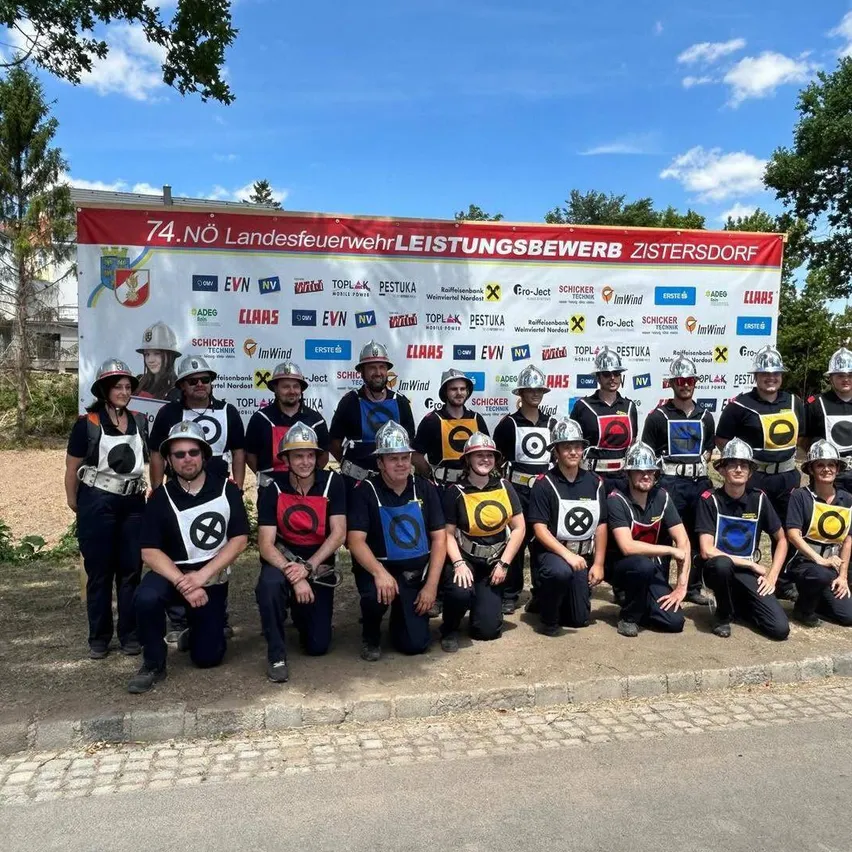 Eine Gruppe Feuerwehrleute in Uniform posiert für ein Foto beim 74. Landesfeuerwehrleistungsbewerb in Zistersdorf.