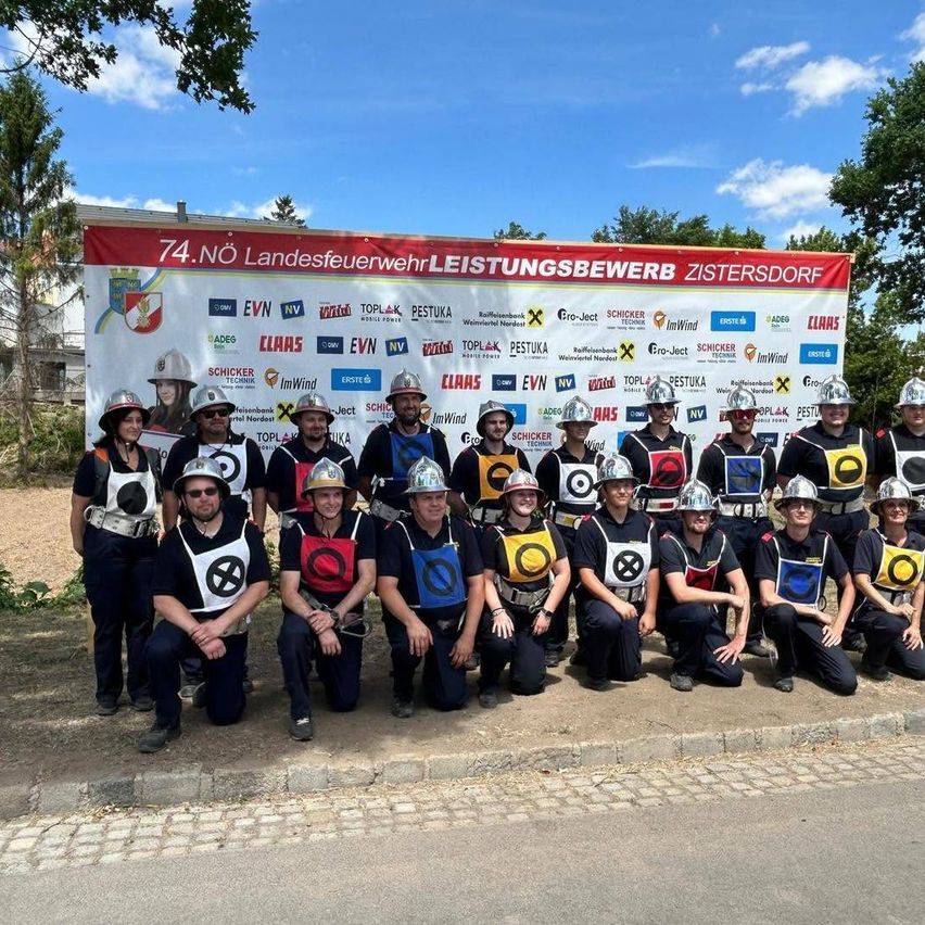 Eine Gruppe Feuerwehrleute in Uniform posiert für ein Foto beim 74. Landesfeuerwehrleistungsbewerb in Zistersdorf.