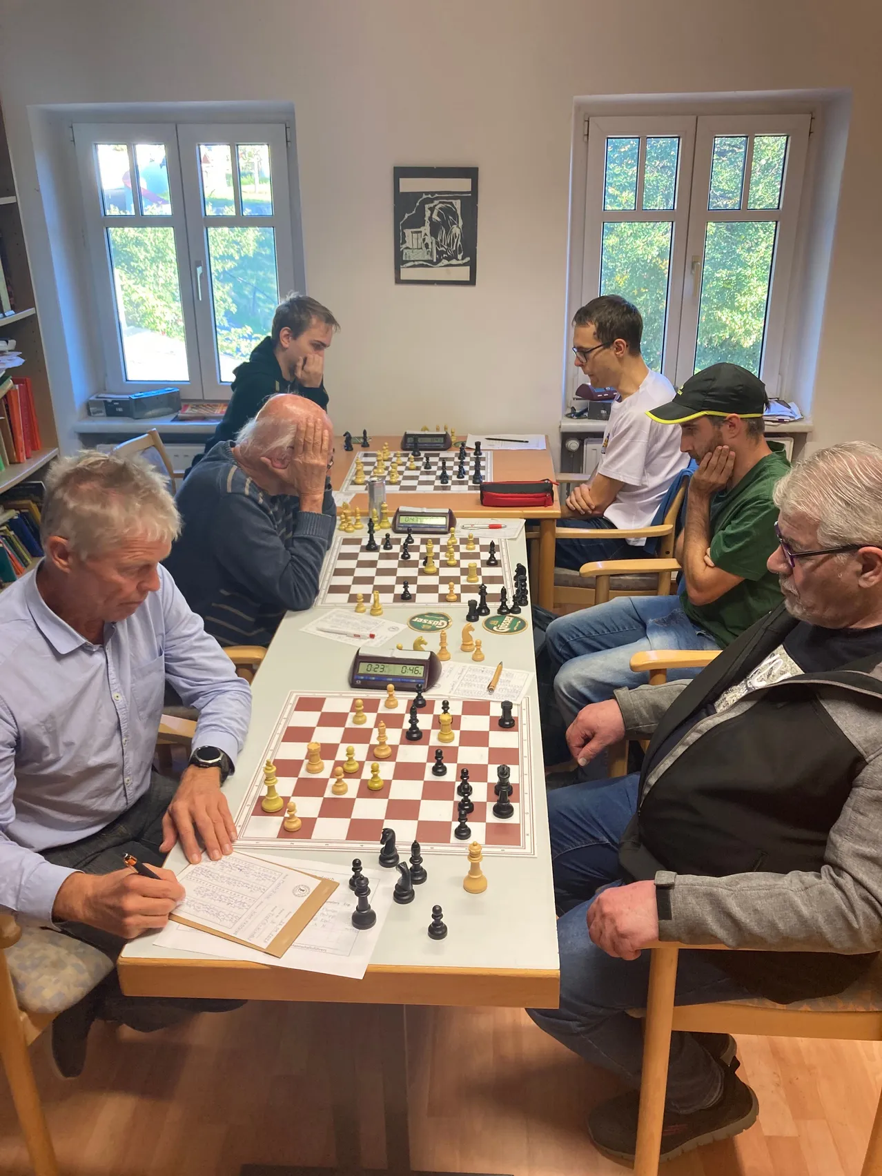 Eine Gruppe von Männern sitzt um einen Tisch herum und spielt Schach.