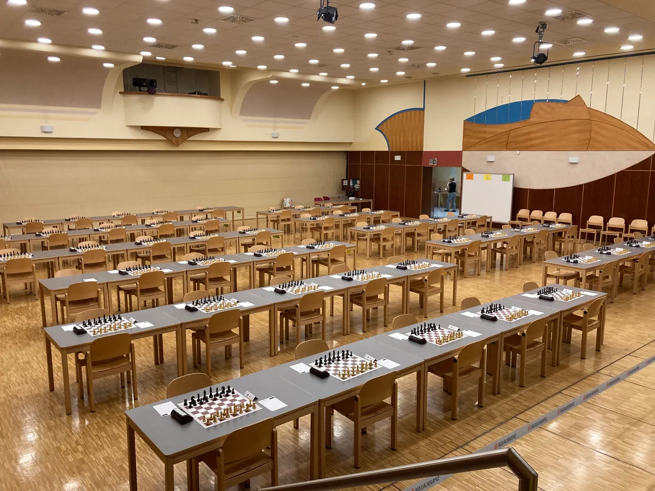Ein großer Raum mit vielen Schachtischen, die in Reihen aufgestellt sind, jeder mit einem Schachspiel darauf.