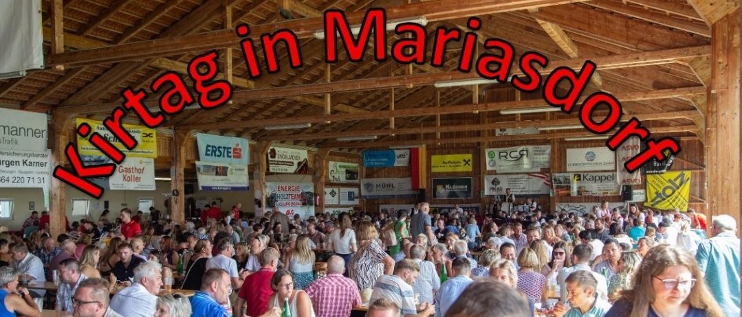 Eine große Menschenmenge versammelt sich drinnen, wahrscheinlich bei einem Festival oder einer Veranstaltung, mit Bannern und Schildern im Hintergrund. Das Datum und die Uhrzeit der Veranstaltung sind prominent angezeigt.