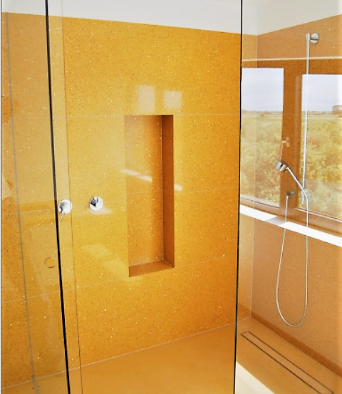 Ein Innenraum eines Duschraums mit gelben Wänden und Glastüren. Ein Fenster mit Blick auf Bäume draußen.
