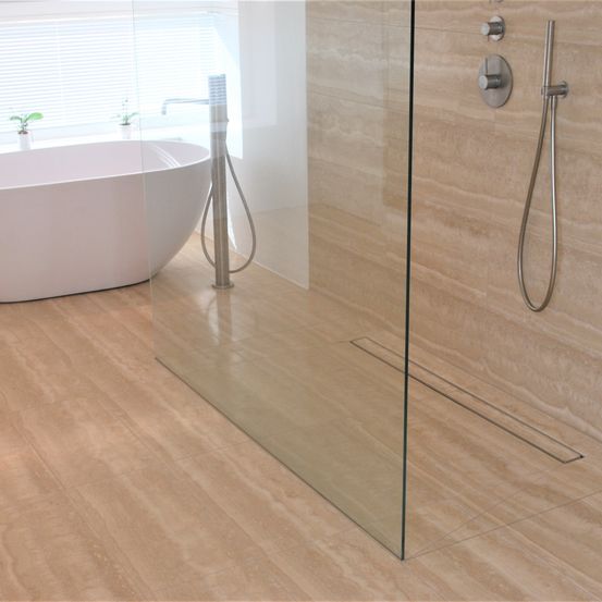 Ein modernes Badezimmer mit einer weißen Badewanne, einer Glasdusche und einer Edelstahl-Duschbrause. Holzböden und geflieste Wände.