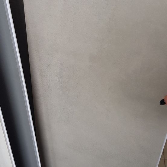 Eine Nahaufnahme einer glatten, hellen Oberfläche mit einem schwarzen Objekt auf der rechten Seite, möglicherweise ein Stift.