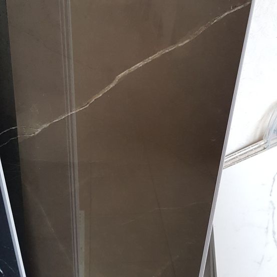 Eine Nahaufnahme einer beigefarbenen Marmorfliese mit einem sichtbaren Riss, der diagonal über die Oberfläche verläuft.