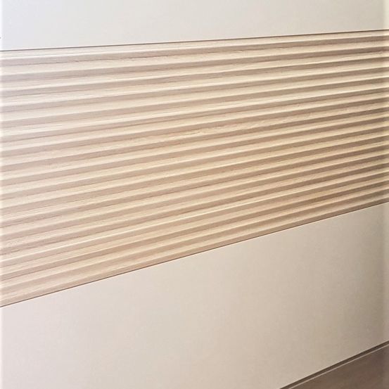 Eine Nahaufnahme einer Wand mit horizontalen Holzlamellen mit einer glatten, hellbraunen Oberfläche. Die Lamellen haben ein schlankes, modernes Aussehen und sind vor einem schlichten weißen Hintergrund gesetzt.