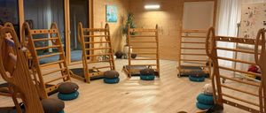 Ein Yogastudio mit Holzboden und -wänden. Holzige Yoga-Ausrüstung und Kissen sind im Raum angeordnet.