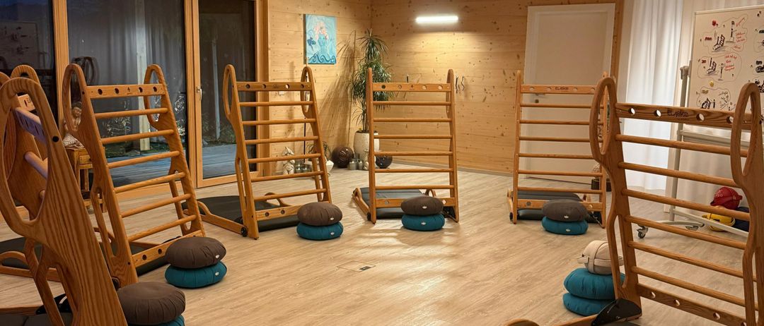 Ein Yogastudio mit Holzboden und -wänden. Holzige Yoga-Ausrüstung und Kissen sind im Raum angeordnet.