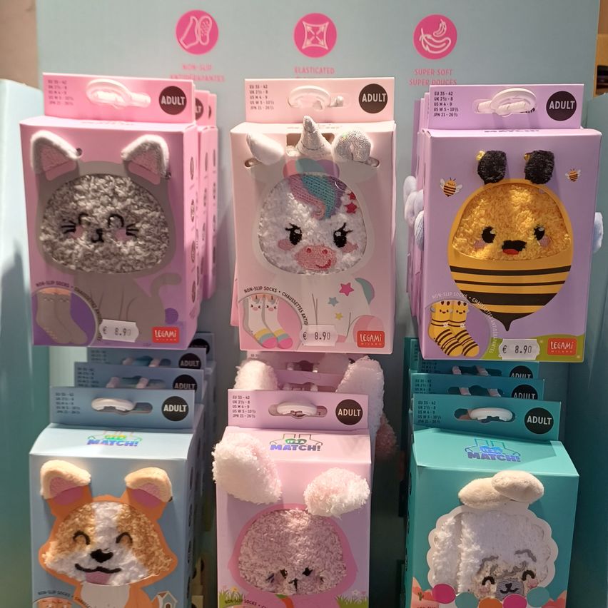 A display of various plush toys in colorful boxes, including a cat, a unicorn, a bee, a fox, and a poodle. Each box is labeled as 'Adult' and priced at 8.90 euros.