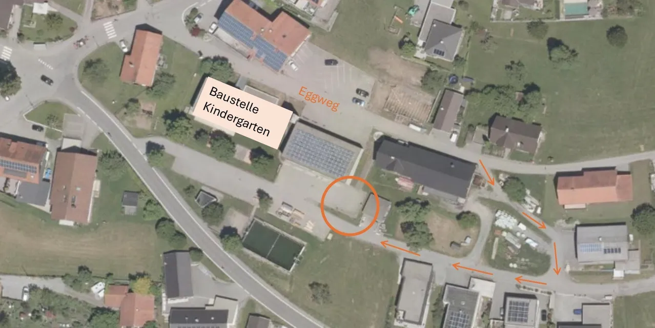 Eine Luftaufnahme eines Kindergartens mit einem Gebäude, das als Baustelle Kindergarten gekennzeichnet ist. Das Gebiet ist von Häusern und einer Straße umgeben. Es gibt einen Tennisplatz und ein Schwimmbad.