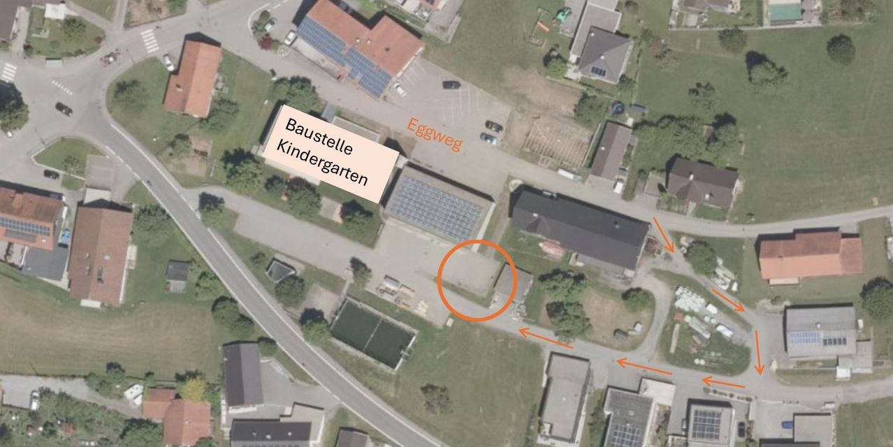 Eine Luftaufnahme eines Kindergartens mit einem Gebäude, das als Baustelle Kindergarten gekennzeichnet ist. Das Gebiet ist von Häusern und einer Straße umgeben. Es gibt einen Tennisplatz und ein Schwimmbad.