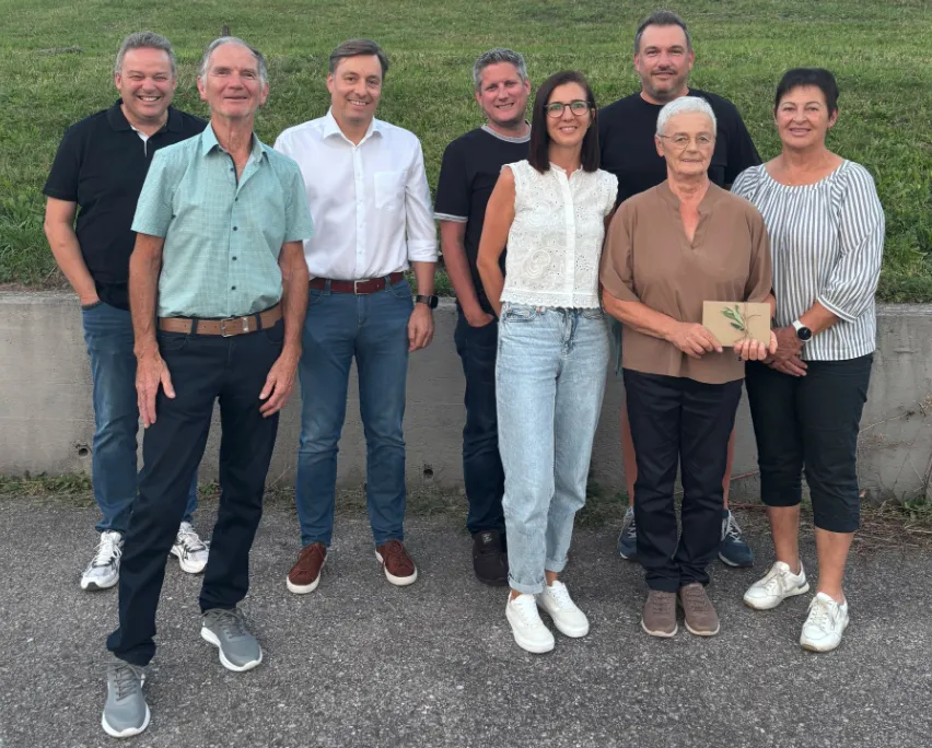 Eine Gruppe von Menschen, die zusammenstehen und für ein Foto lächeln. Sie sind lässig gekleidet und scheinen für ein Gruppenfoto zu posieren.