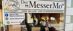 Schaufenster mit einem Schild 'Der MesserMo', das Messer, Beratung, Verkauf und Service anbietet. Im Inneren sind Gegenstände auf Regalen ausgestellt.