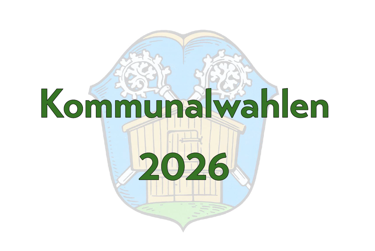 Ein Logo für die Kommunalwahlen 2026 mit einem Schild, der eine Scheune und zwei dekorative Elemente darüber zeigt, in Grün und Blau.