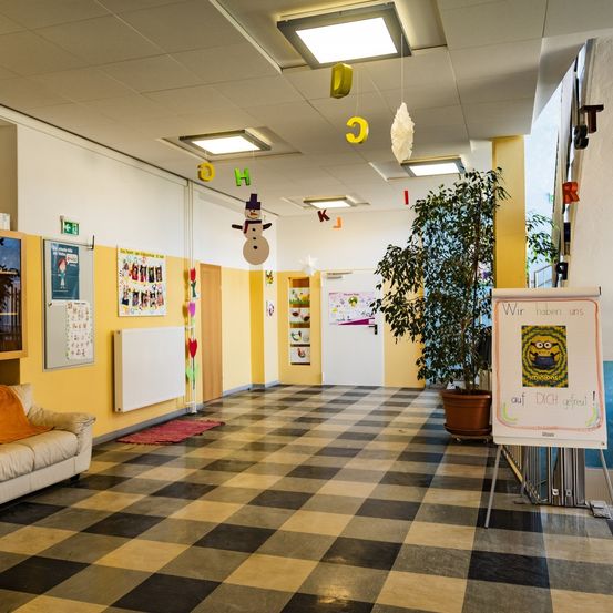 Ein Flur mit gelben Wänden, einem Schachbrettboden und einer Couch. Dekorationen und ein Schneemann hängen von der Decke.