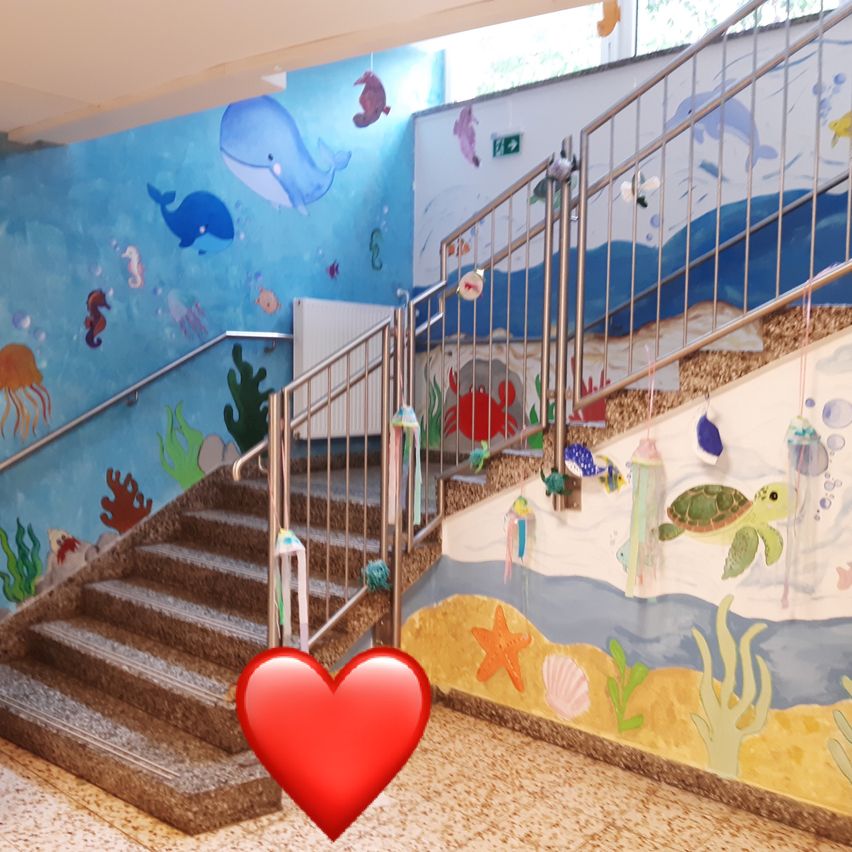 Eine Treppe mit Handläufen und Meereslebensmurals an den Wänden, einschließlich eines Herzsymbols in der Mitte.