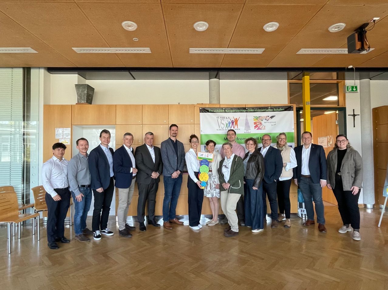 Gruppe von Fachleuten und Studenten posiert für ein Foto in einem Konferenzraum mit einem Banner dahinter.