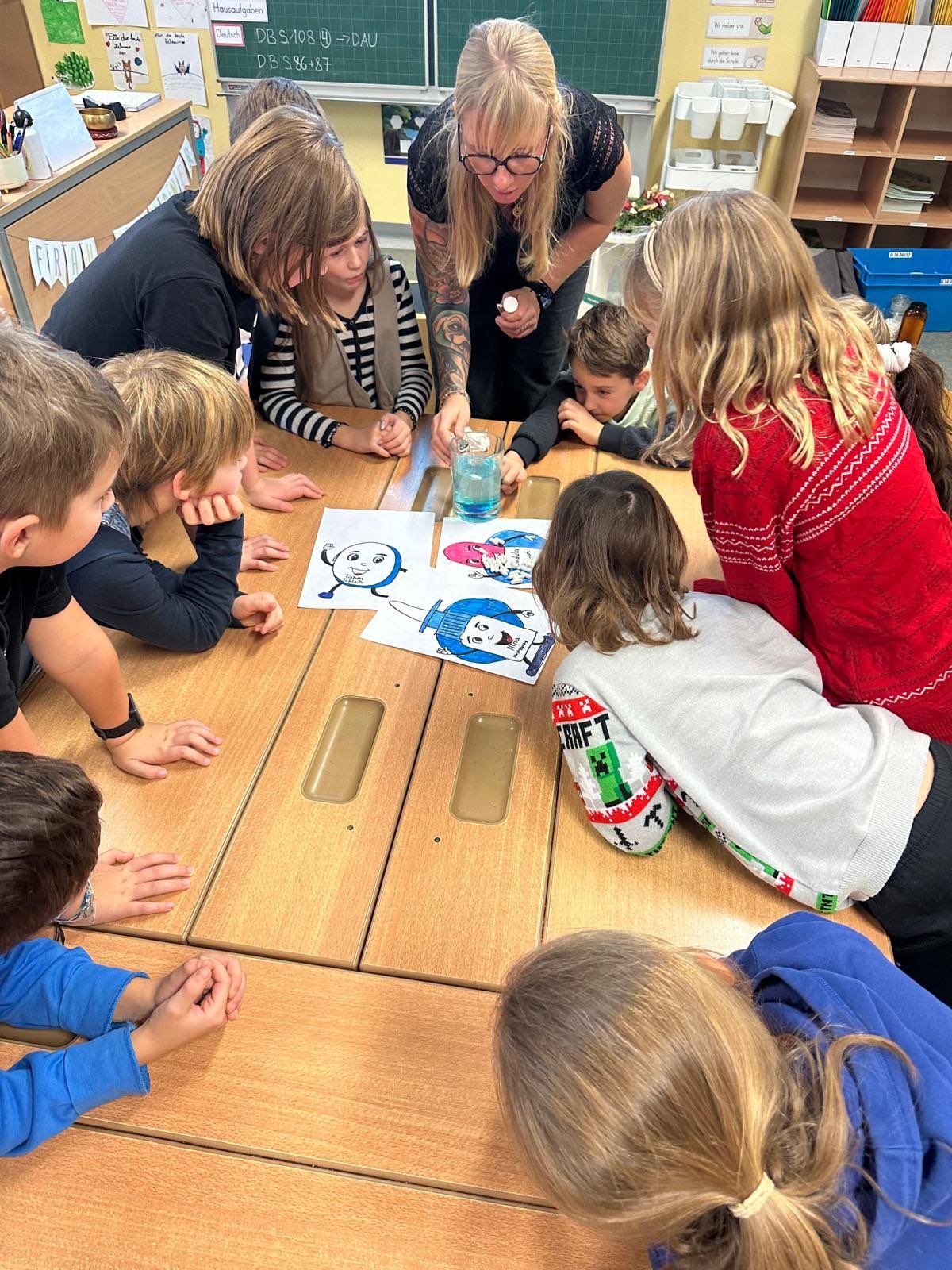 Eine Gruppe von Kindern und zwei Erwachsenen versammelt sich um einen Tisch und betrachtet Malvorlagen. Die Kinder sind engagiert und konzentriert, während die Erwachsenen ihnen helfen.