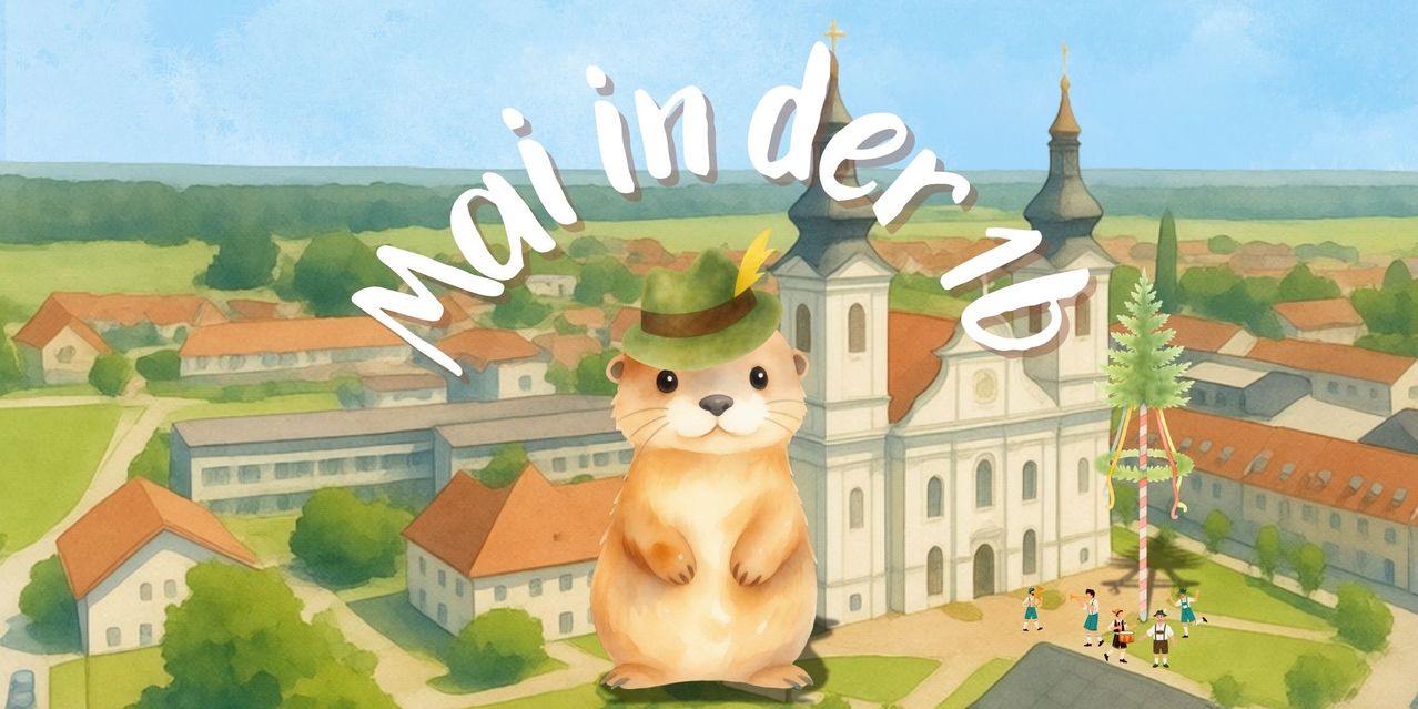 A groundhog wearing a green hat stands in front of a church with a cross on top. The groundhog is in front of a building with red roofs and windows.