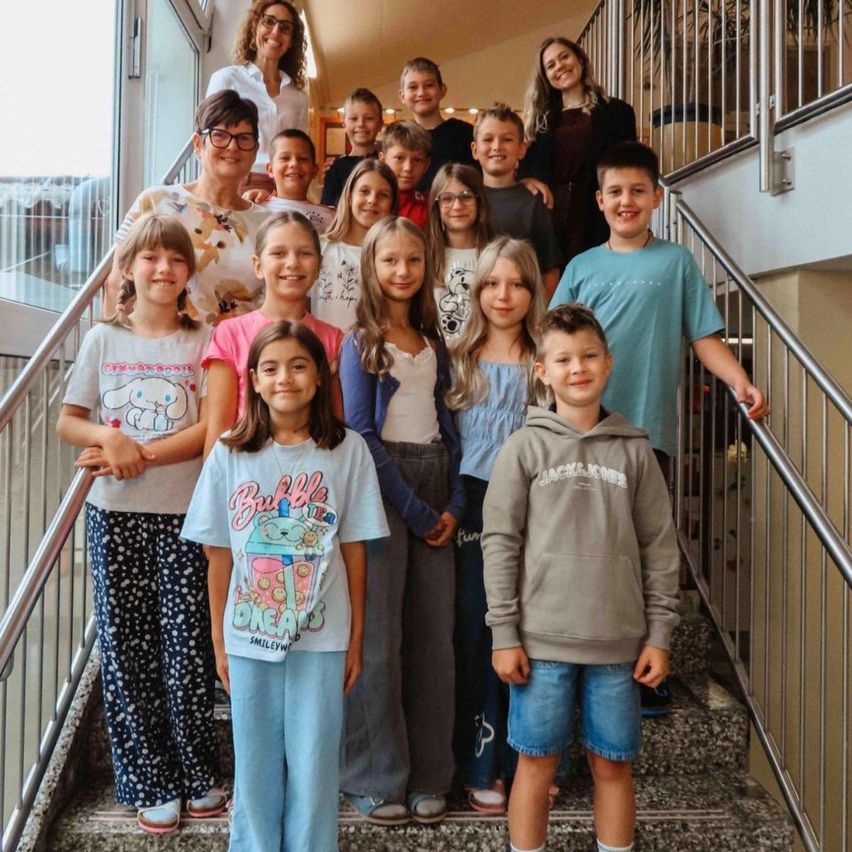 Eine Gruppe von Kindern und Erwachsenen steht auf einer Treppe und lächelt für ein Foto.
