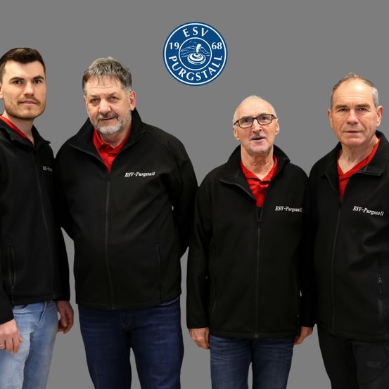 Vier Männer stehen zusammen und tragen alle schwarze Jacken mit 'ESV-Purgastall' darauf. Sie lächeln und scheinen für ein Foto zu posieren.