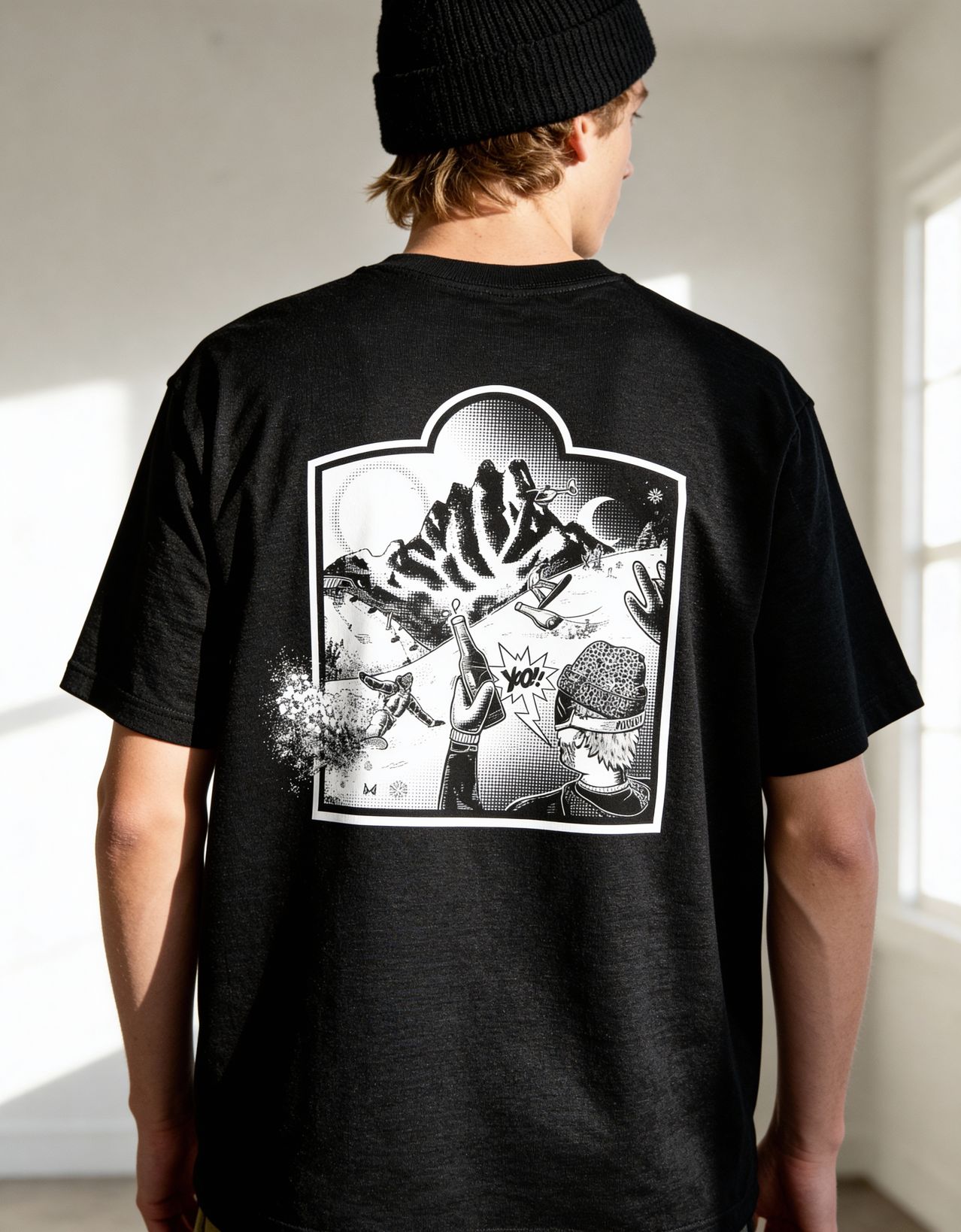 Eine Person trägt ein schwarzes T-Shirt mit einem weißen Grafikdesign einer Person, die mit einer Flasche, einem Mond und Bergen Ski fährt.