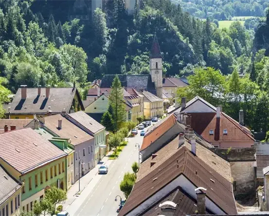 Eine Stadt mit vielen Häusern, Autos und Bäumen. Die Straße ist in der Mitte. Der Himmel ist klar.