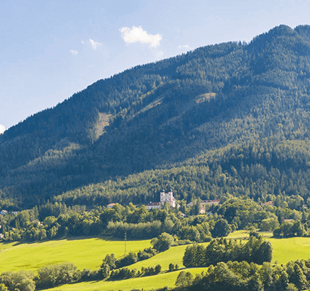Ein Berg mit üppigem Grün und einem weißen Gebäude unter einem klaren Himmel mit weißen Wolken.
