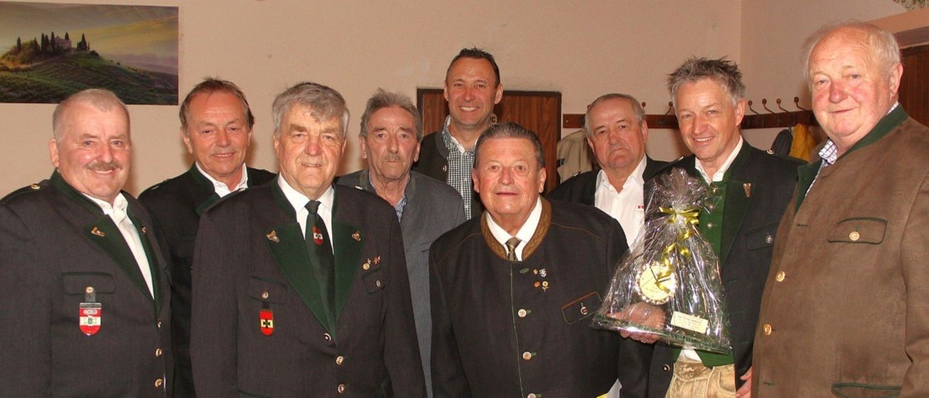 Eine Gruppe von Männern in traditioneller Kleidung steht zusammen, ein Mann hält eine Trophäe, andere tragen Medaillen, die Bildunterschrift lautet OKB-Vorstand mit Bez-Kommandant.