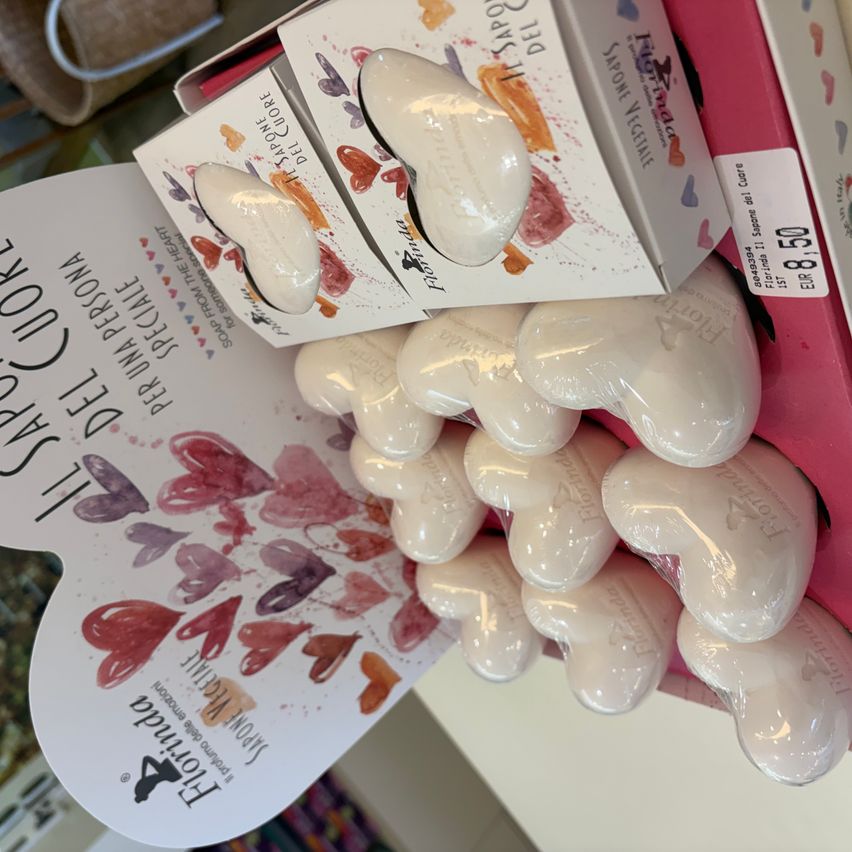 A box of heart-shaped soaps with floral designs on a white background. The soaps are displayed on a white shelf with a pink background.