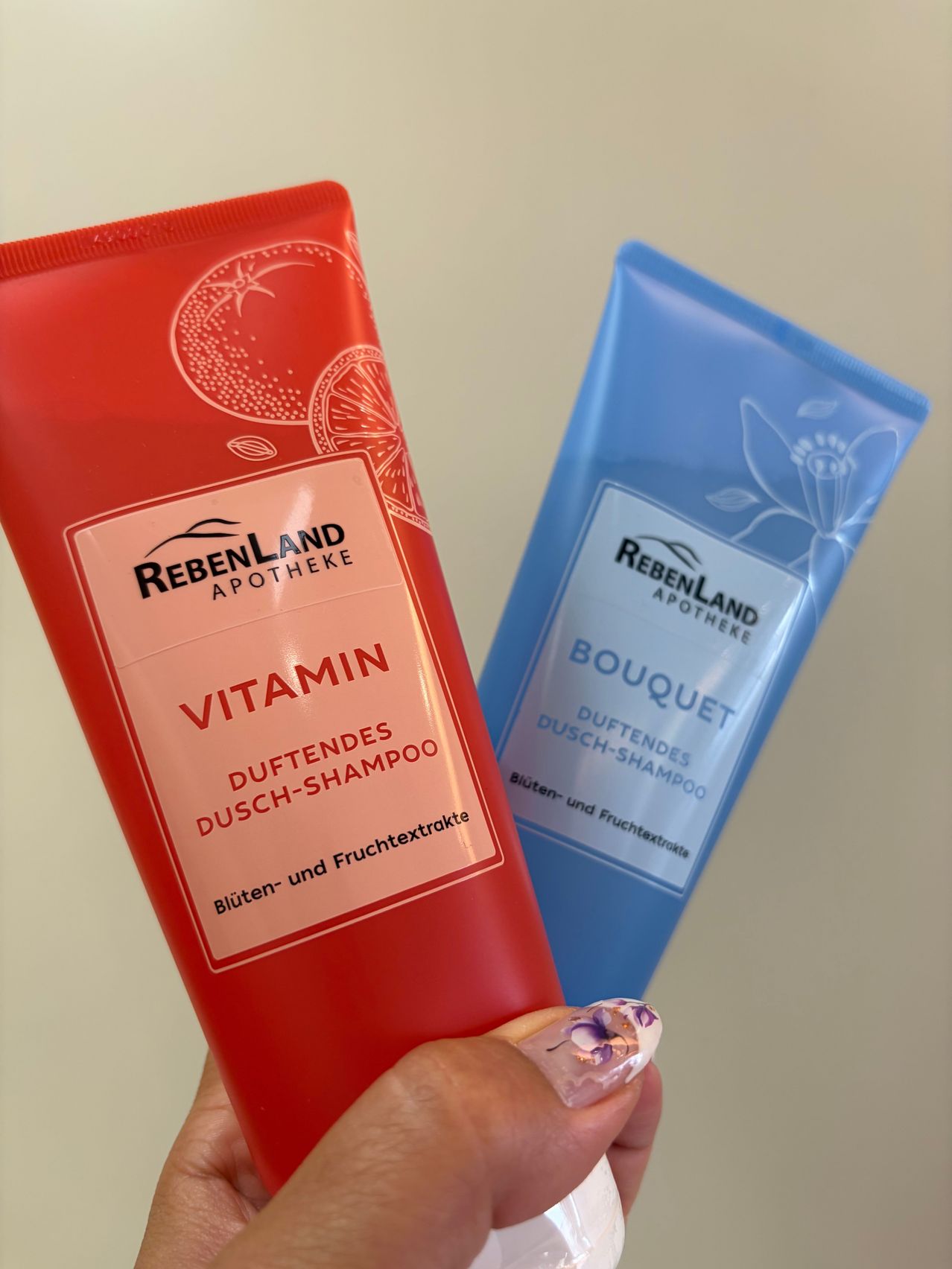 Two tubes of shampoo, one red and one blue, are held in a hand. The red tube is labeled Vitamin Duftendes Dusch-Shampoo, and the blue tube is labeled Bouquet Duftendes Dusch-Shampoo.
