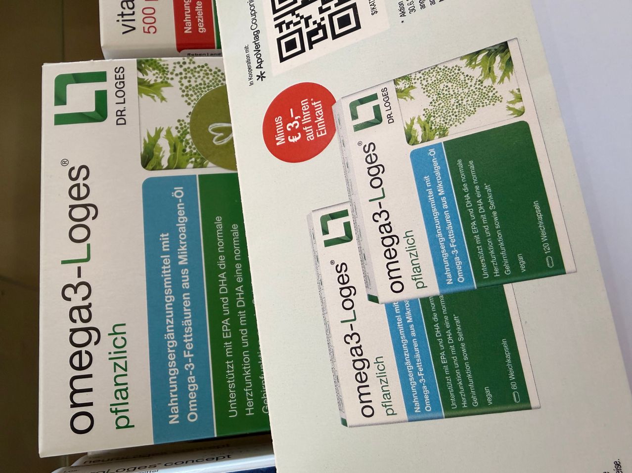 A stack of omega-3 capsules, each labeled with a plant icon and a price discount. The front has a red circle with 'minus 3' and 'Einkauf' on it.