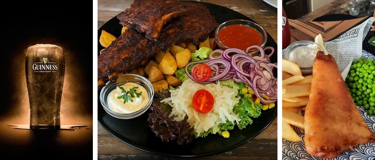 Ein schwarzer Teller enthält geräucherte Rippchen, Kartoffeln und Salat mit Zwiebeln, Tomaten und Mais. Ein kleines Schälchen cremiger Sauce und ein Becher Ketchup sind ebenfalls auf dem Teller.