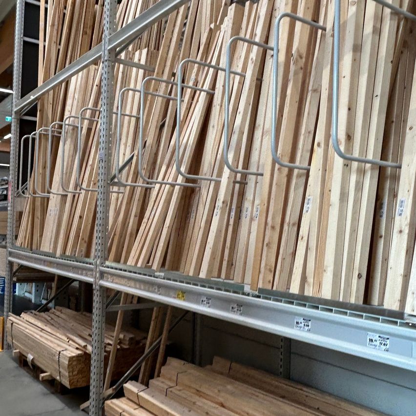 Ein Lagerraum mit ordentlich organisierten Holzbrettern auf Metallregalen, mit Metallhalterungen zur Unterstützung.