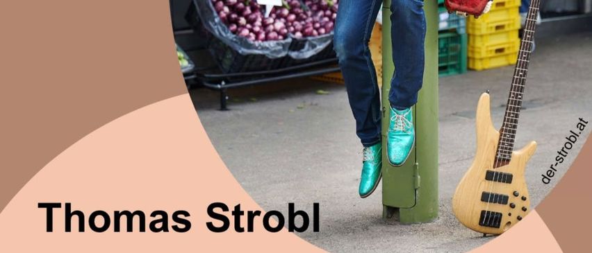 Ein Mann mit Gitarren und Akkordeon steht in einem Markt und bewirbt ein Kabarett von Thomas Strobl.