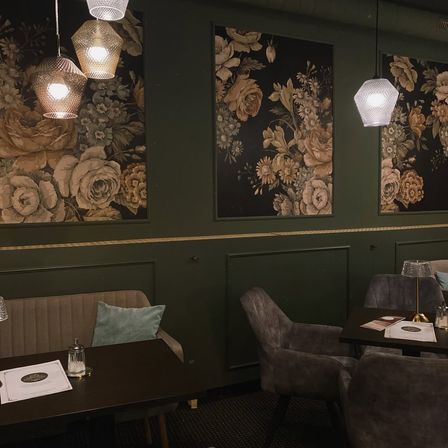 Ein Innenansicht eines Essbereichs in einem Restaurant mit drei floralen Wandgemälden und einigen Tischen und Stühlen.