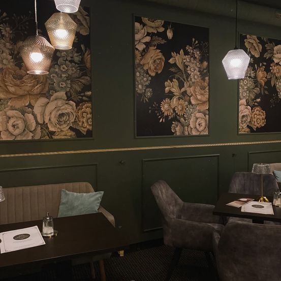 Ein Innenansicht eines Essbereichs in einem Restaurant mit drei floralen Wandgemälden und einigen Tischen und Stühlen.