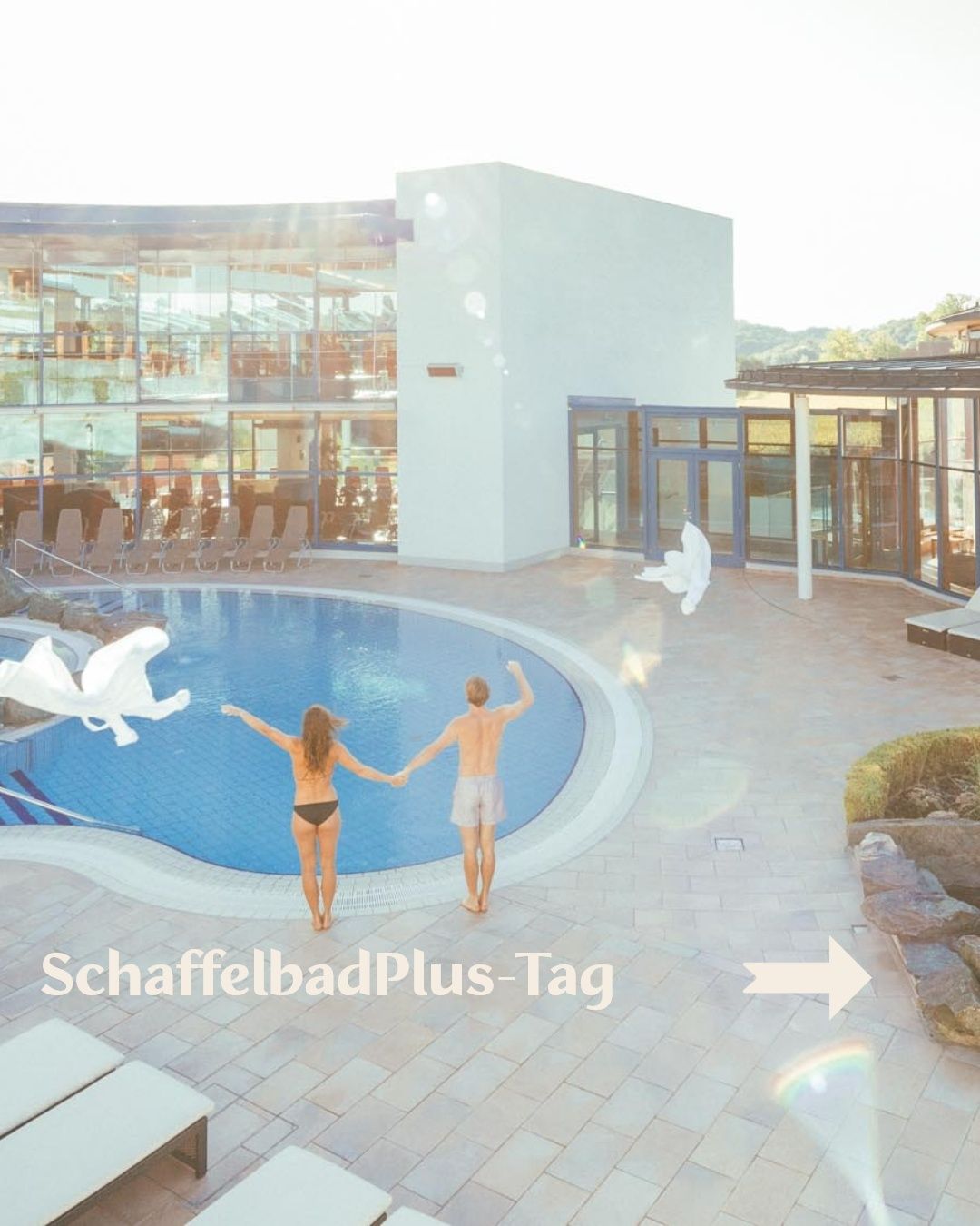 Zwei Menschen halten Händchen vor einem Pool, wobei ein weißer Pfeil nach rechts zeigt. Der Pool ist von einer Terrasse mit einer Glaswand und Liegestühlen umgeben.