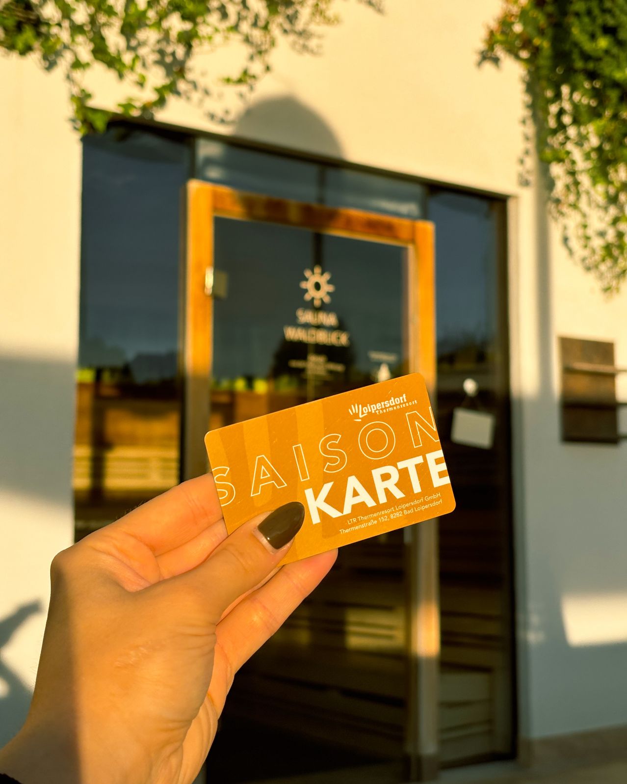 Eine Person hält eine Saison Karte vor einem Gebäude mit Glastüren und einem Holzrahmen.