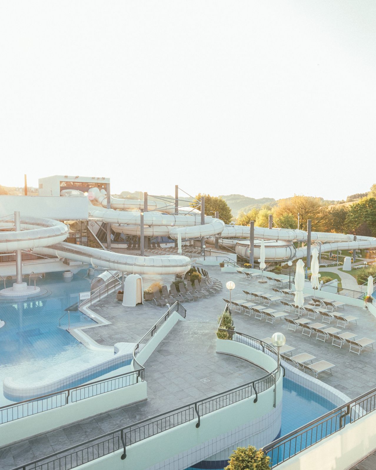 Ein Wasserpark mit mehreren Wasserrutschen und Pools, umgeben von Liegestühlen und Sonnenschirmen.