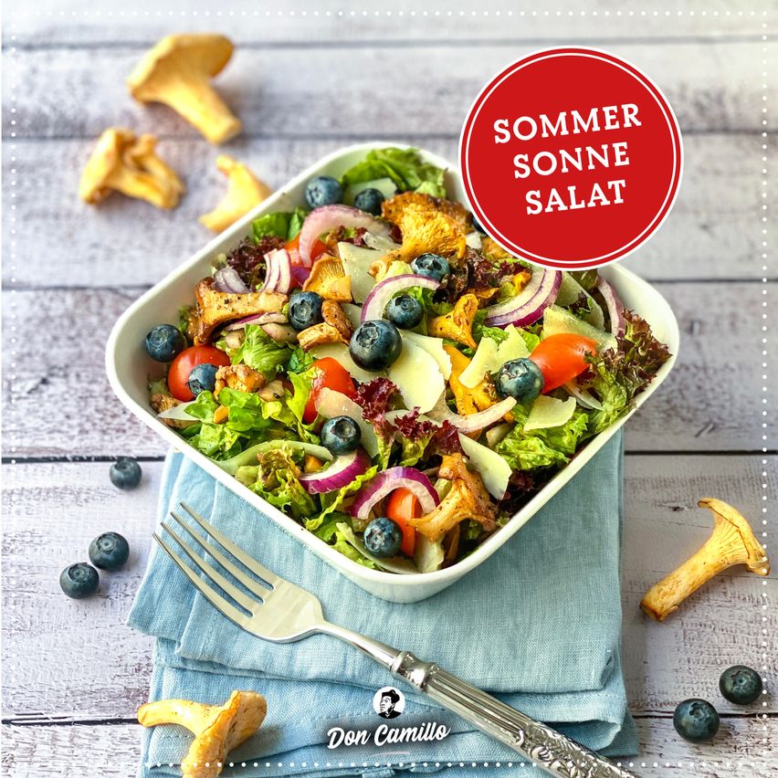 Eine Schüssel Salat mit verschiedenen Gemüsesorten, einschließlich Blaubeeren, Tomaten und Pilzen, auf einem Holztisch mit einer Gabel. Ein rotes Schild sagt Sommer Sonne Salat.