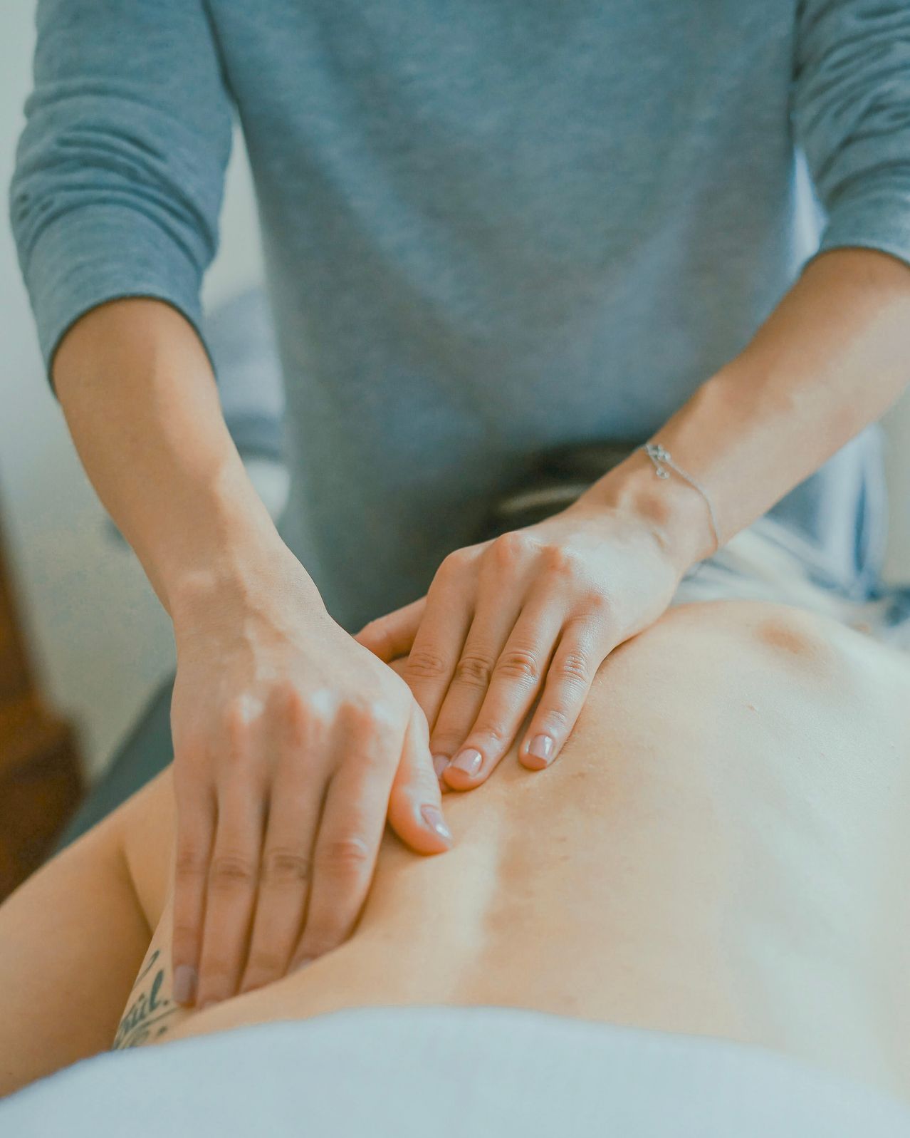 Eine Person bekommt von einer anderen Person eine Massage am Rücken. Eine Hand liegt auf der Schulter, die andere auf dem Rücken.