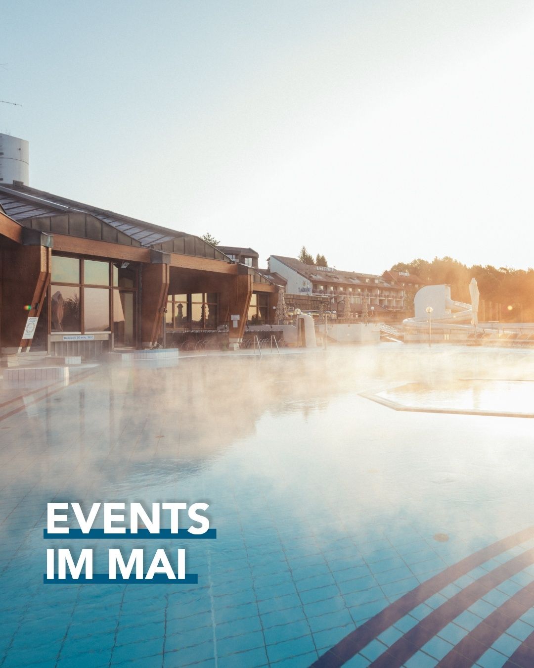 Ein großer Außenpool mit aufsteigendem Dampf, umgeben von einem Gebäude mit Glasfenstern. Im Hintergrund sind Bäume zu sehen. Die Worte 'Events im Mai' sind unten in Blau angezeigt.