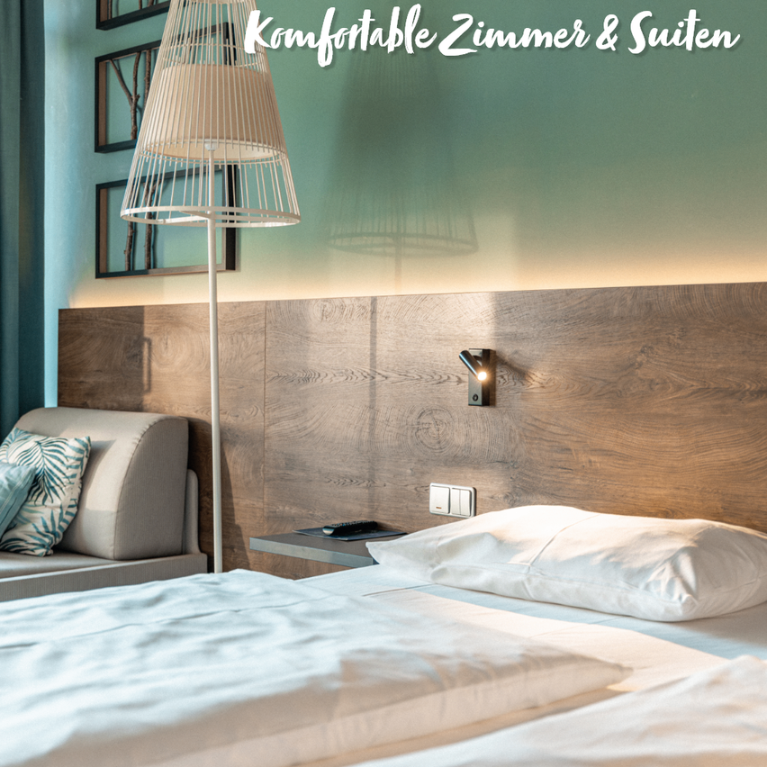 Ein ordentlich gemachtes Bett mit weißen Laken und Kissen in einem Hotelzimmer mit einem hölzernen Kopfteil. Eine Lampe und eine Fernbedienung sind auf einem Nachttisch.