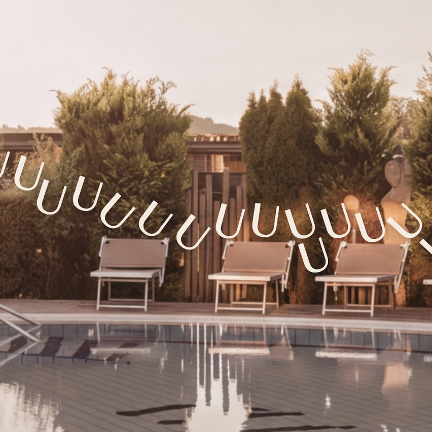 A serene pool area with lounge chairs and greenery, featuring a modern design. The chairs are neatly arranged around the pool.