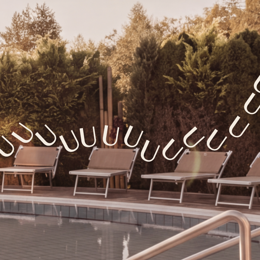 A serene pool area with four lounge chairs and a metal handrail, surrounded by neatly trimmed hedges and trees.