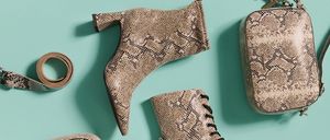 Eine Auswahl an Schuhen, darunter schwarze Stiefel, braune Schlangenmuster-Ankle-Boots, ein Gürtel und eine Umhängetasche auf blauem Hintergrund.