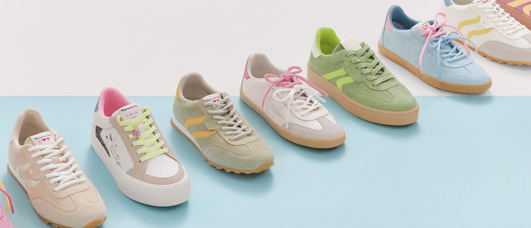 Sechs Sneaker in Pastelltönen sind auf einem blauen Hintergrund angeordnet. Sie sind in einer Reihe aufgereiht. Die Sneaker haben farbenfrohe Schnürsenkel und Designs.