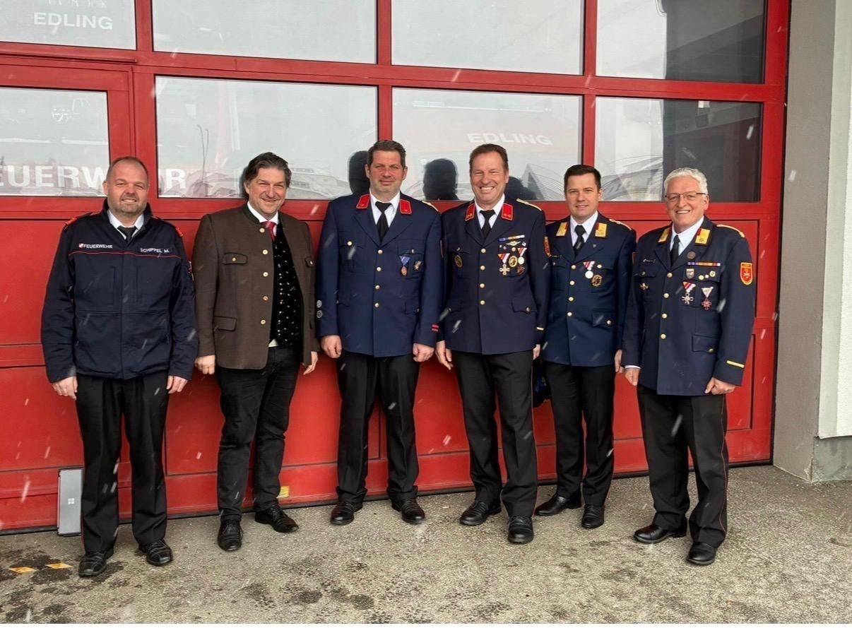 Sechs Männer in Uniform, möglicherweise Militäroffiziere, stehen in einer Reihe vor einer roten Wand. Sie tragen alle Medaillen und schwarze Schuhe.